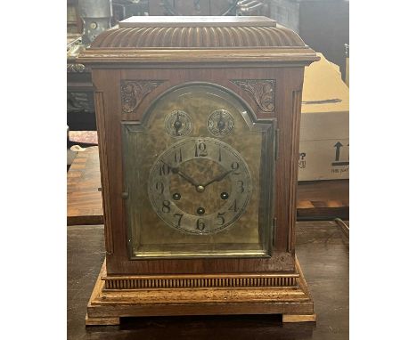 Early 20th Century mantel clock by Jung Hans with arched brass and silver dial, three train brass movement and set in a carve