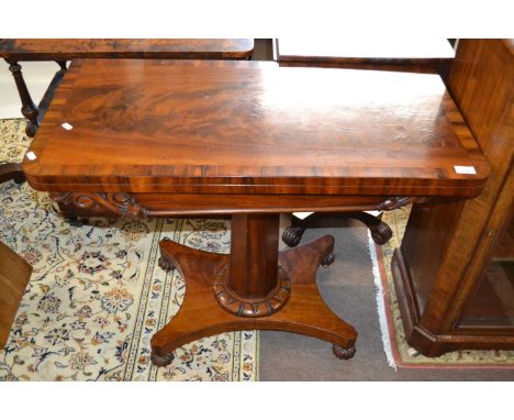 A Victorian flame mahogany veneered card table with folding and rotating baize lined top over an octagonal column, platform b