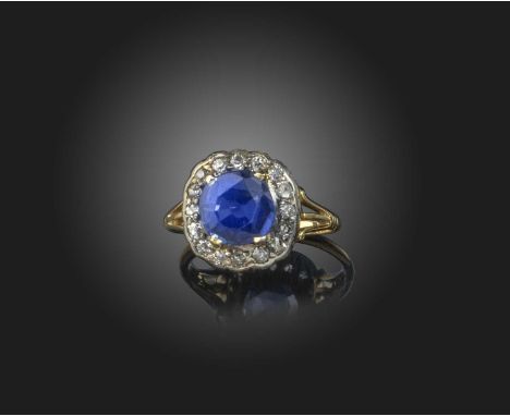 A sapphire and diamond cluster ring, set with a circular-cut blue sapphire within a surround of diamonds in silver and gold, 