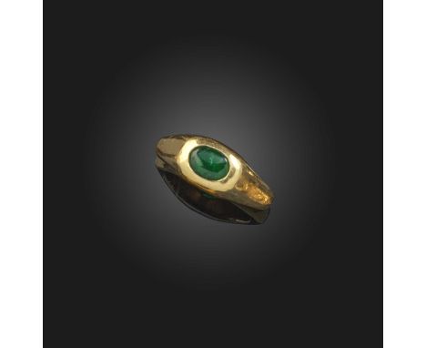 An emerald solitaire ring, the emerald cabochon set within hammered yellow gold setting, size T, 23g