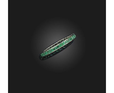 An emerald eternity ring, channel-set with a continuous band of calibré-cut emeralds, mounted in platinum, size O1/2