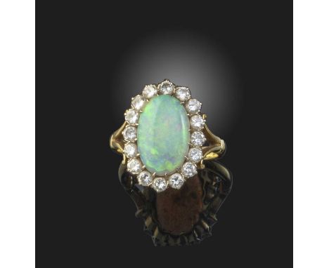 An opal and diamond cluster ring, the oval opal set within a surround of diamonds in bifurcated yellow gold setting, size M