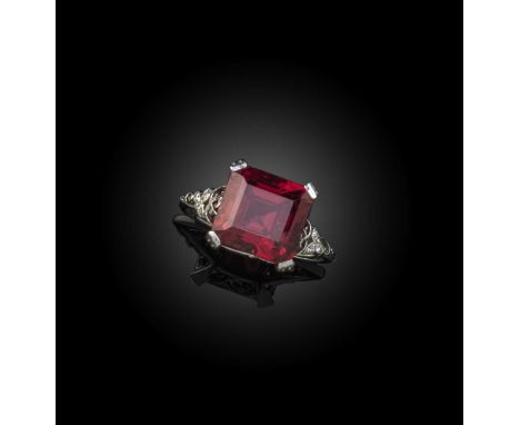 A red spinel and diamond ring, the step-cut spinel weighing 5.29cts, claw-set within pierced scrolling gallery and shoulders 