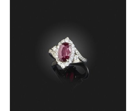 A ruby and diamond cluster ring, set with an oval ruby within a tapered surround of diamonds and diamond-set shoulders in whi
