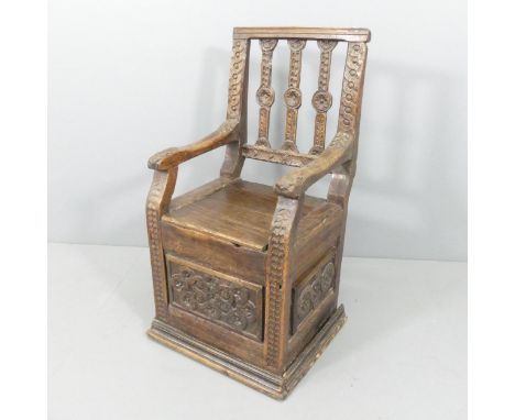 A 17th/18th century panelled oak box seat armchair, with chip carved decoration, panelled sides and lifting seat. Overall 55x