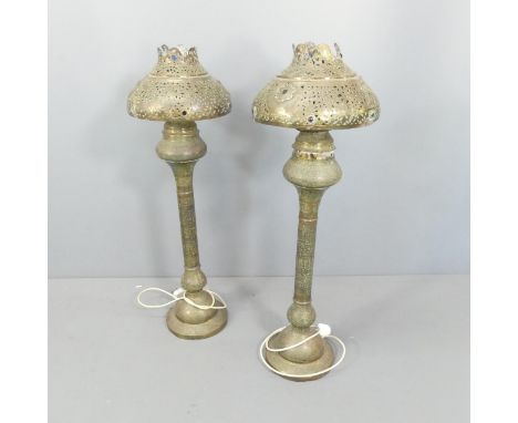 A pair of Morrocan style brass floor lamps, with pierced and repousse decoration. Height overall 107cm.Some dents and scratch