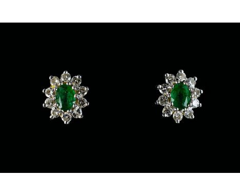 A Pair Of Diamond And Emerald Cluster Stud Earrings The central green emeralds surrounded by 10 brilliant cut diamonds, fully