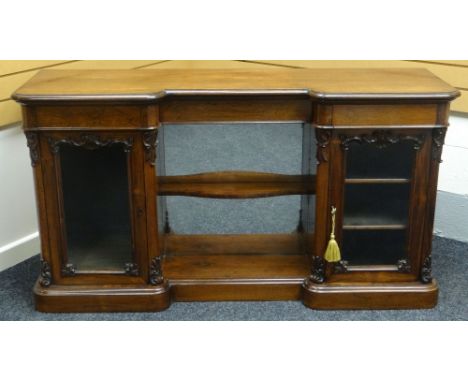 A rosewood break-front credenza having two single door glazed cabinets flanking a mirrored open-shelved centre recess, circa 