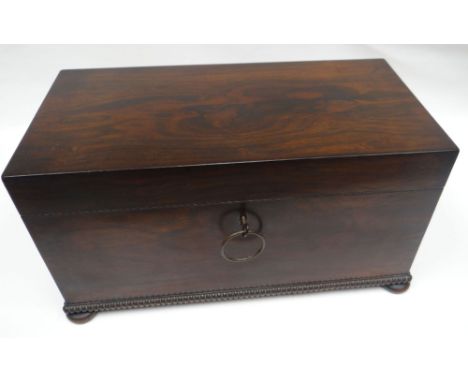 A George IV large rosewood tea-caddy of plain box-form on bun feet with beaded lower border and metallic wreath-form ring han