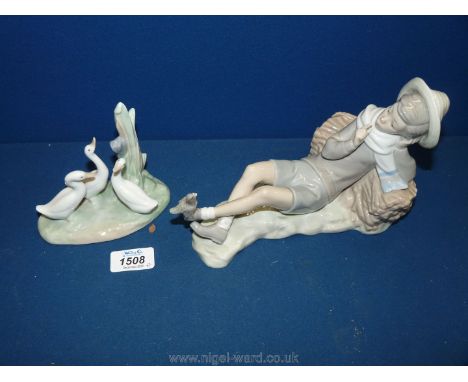 A Lladro figure of boy lying on a haystack with a bird on his foot, 8" long together plus a Nao figure of three ducks on a pl