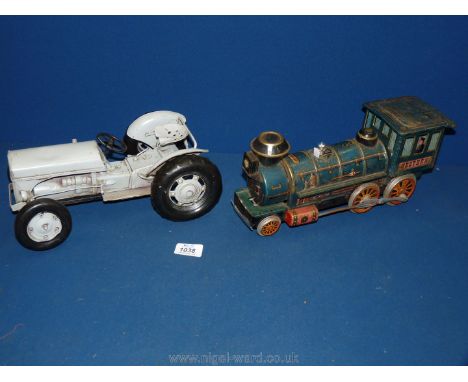 A vintage tin plate battery operated train and grey metal toy tractor.