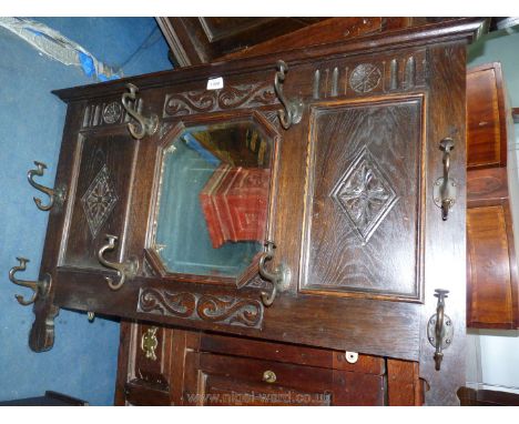 An Oak wall hanging Coat and Hat Rack with central eight sided bevelled mirror and bronzed hooks and with panelled and carved