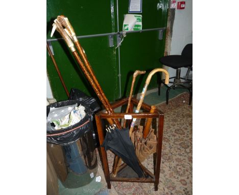 A triangular stick stand complete with five walking sticks (three with horn handles), a parasol and umbrella.