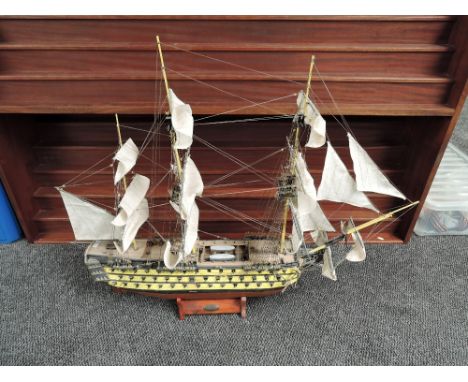 A hand made wooden and painted scale model, 1765 HMS Victory, complete with cannons and rigging, on wooden stand, length 90cm