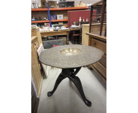 A 19th Century Eastern brass topped table with ornately carved tripod base