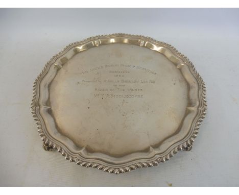 A silver salver with gadrooned border raised upon four scrolled supports, Birmingham 1964, bearing inscription: 'The Ansells 