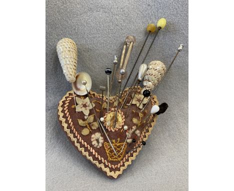 A quantity of hat pins including MOP, on a felt heart shaped cushion.