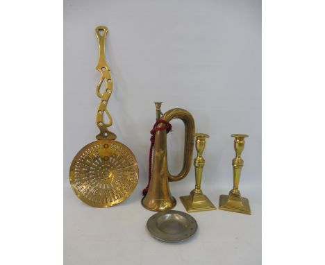 A brass skimmer, a pair of brass candlesticks and a brass bugle. 