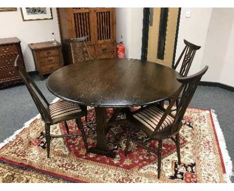 An Ercol elm drop leaf dining table and four wheel backed chairs with striped cover 