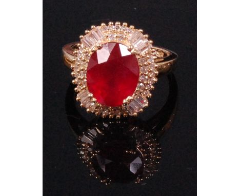 A contemporary 14ct yellow gold ruby and diamond cluster ring, arranged as a centre four claw set oval cut ruby weighing appr