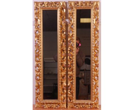 A pair of 19th century Florentine giltwood and gesso framed wall mirrors, having bellflower moulded slips within scroll leaf 