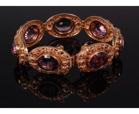 A ladies 9ct yellow gold and amethyst gatelink bracelet, each oval cut amethyst weighing approx. 4.5ct, in a pierced scroll w