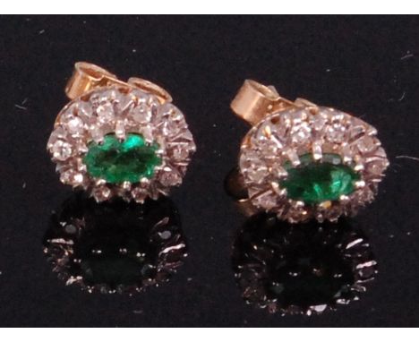 A pair of 9ct gold emerald and diamond set ear studs, arranged as a centre oval cut emerald in a surround of small brilliants