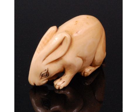 A Japanese carved ivory netsuke of a crouching rabbit, having penwork eyes, signed verso, Meiji period, w.4.2cm  Condition Re