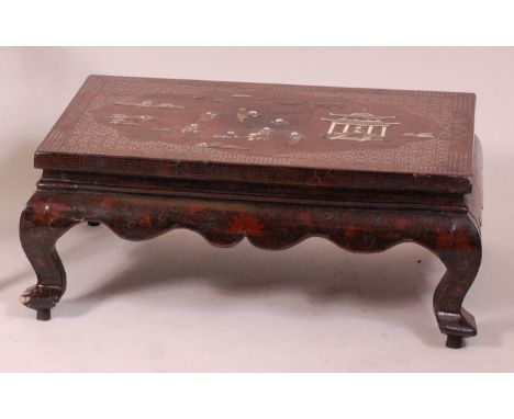 A late 19th century Japanese chinoisserie lacquered and Shibyama low occasional table, the top inlaid in hardstones with figu