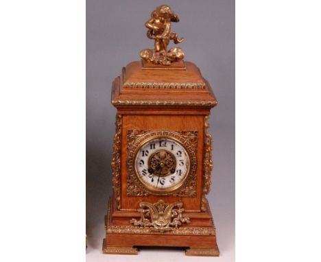 A circa 1900 German oak cased mantel clock, surmounted with a cast brass cherub, case with further brass mounts, white enamel