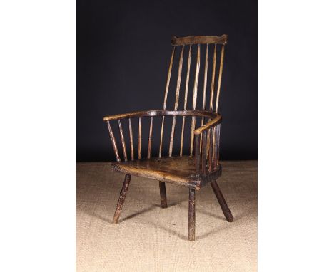 An 18th Century Primitive Ash & Elm Comb-back Windsor Armchair attributed to the West Country. The top rail above seven long 