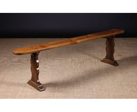 A Long 19th Century Cherrywood Bench. The narrow plank seat with rounded ends pierced by square tenons of the shaped end supp