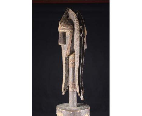 An Early 20th Century Bamana Merekun Puppet. The piece is made of wood, metal plate and shows the remains of red cloth, 41 ½ 