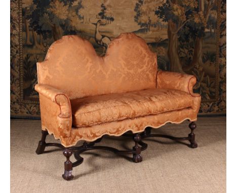 A Small William & Mary Style Camel Backed Settee. The shaped back, scroll arms,s feather-filled swab cushion and serpentine s