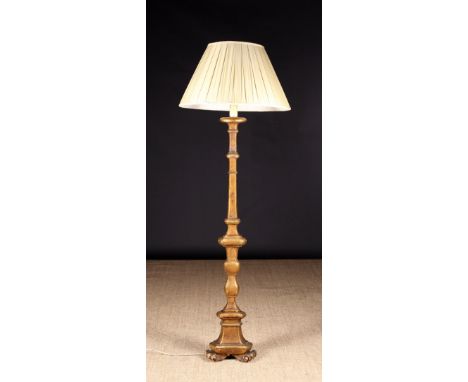 A Giltwood Standard Lamp with a cream pleated shaped on a knopped triangular stem leading down to a scrolling tripod base.