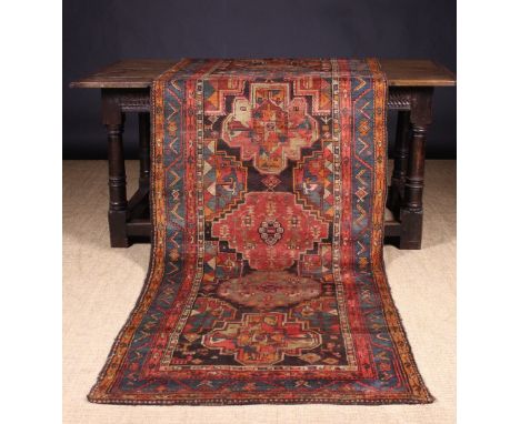 An Old Carpet Runner woven with six medallions in a banded border in beige, dark rose, blue, orange and brown, 114 ins x 39 i