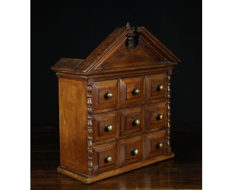 A 19th Century Mahogany Spice Cupboard having a architectural pediment above nine fielded panel drawers centred by brass stud