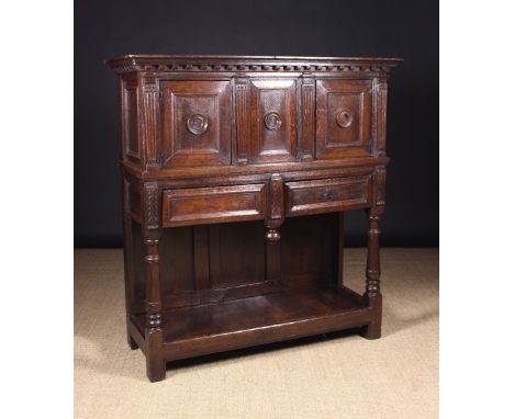 A 16th Century Franco Flemish Oak Buffet. The dentil moulded top above an upper cupboard with three moulded panels centred by