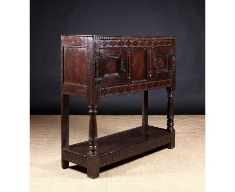 A 17th Century Oak Livery Cupboard having two panel doors flanking a centre panel decorated with punchworked lozenge motifs a