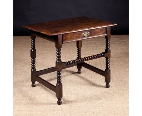 A 17th Century Oak Side Table. The rectangular top with moulded edge above a single frieze drawer hung on side runners, edged