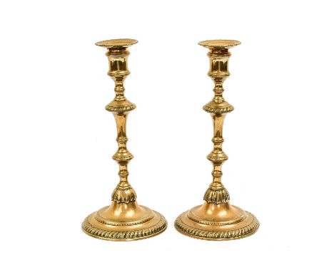 A Pair of Brass Candlesticks, mid 18th century, with circular drip pans, waisted sockets, knopped stems and circular feet27cm
