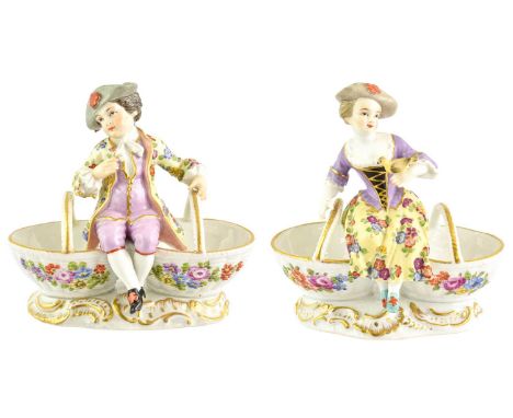 A Matched Pair of Meissen Style Porcelain Figural Sweetmeat Dishes, circa 1900, modelled as 18th century figures seated on tw