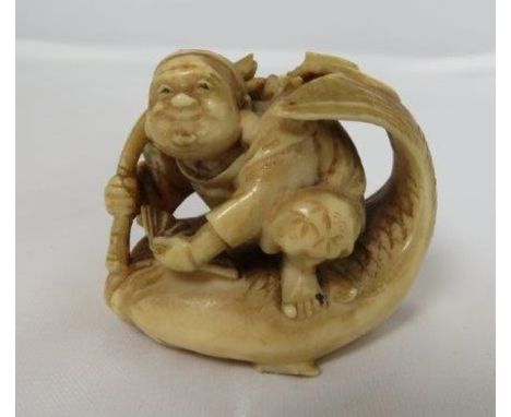 An early 20th century Japanese ivory netsuke of male figure riding a fish, 3cm high