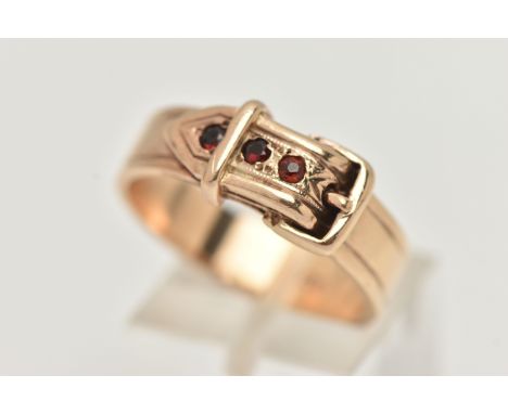 A YELLOW METAL BUCKLE RING, approximate width at widest point 8.2mm, belt set with three circular cut garnets, stamped 9ct, r