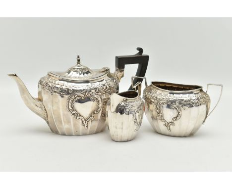 AN EARLY 20TH CENTURY, SILVER TEA SET, comprising of a teapot, sugar bowl and milk jug, each with embossed foliate pattern wi