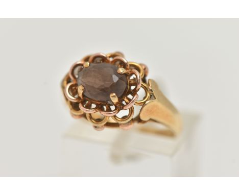 A YELLOW METAL SMOKY QUARTZ RING, set with an oval cut smoky quartz, in a four claw open work setting, scroll shoulders leadi