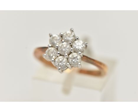 A 9CT GOLD CLUSTER RING, seven circular cut cubic zirconia, prong set in white gold, leading onto a pinched shoulder yellow g