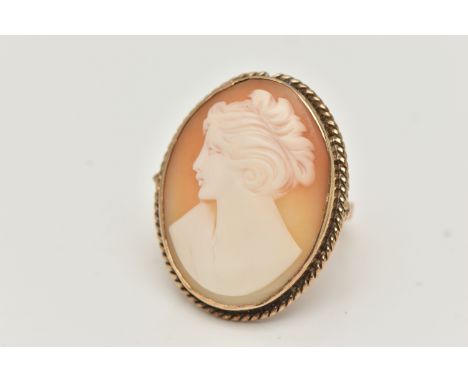A YELLOW METAL CAMEO RING, large oval carved shell cameo depicting a lady in profile, collet set within a rope twist surround