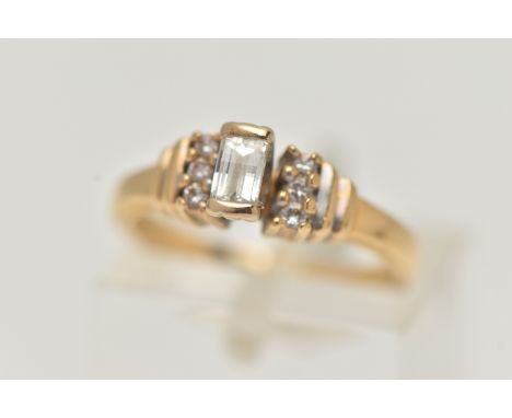 AN 18CT GOLD DIAMOND RING, a baguette cut diamond, half bezel set in yellow gold, approximate diamond weight 0.14ct, flanked 