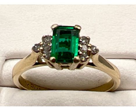 Ladies 9ct gold green stone and diamond ring. Featuring emerald cut stone and 4 round brilliant cut diamonds on each shoulder